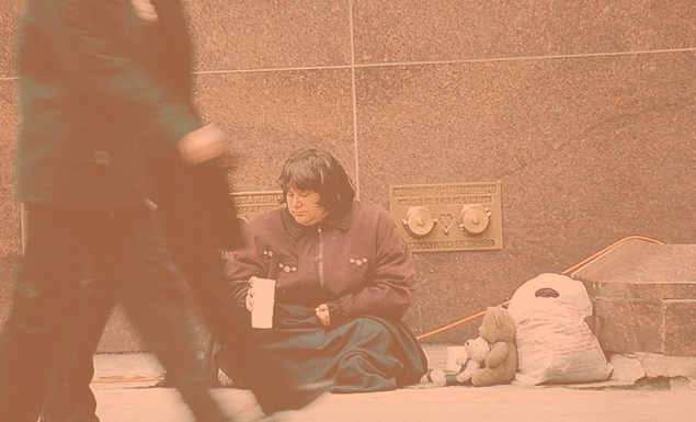 Homeless woman on side of building trying to get change