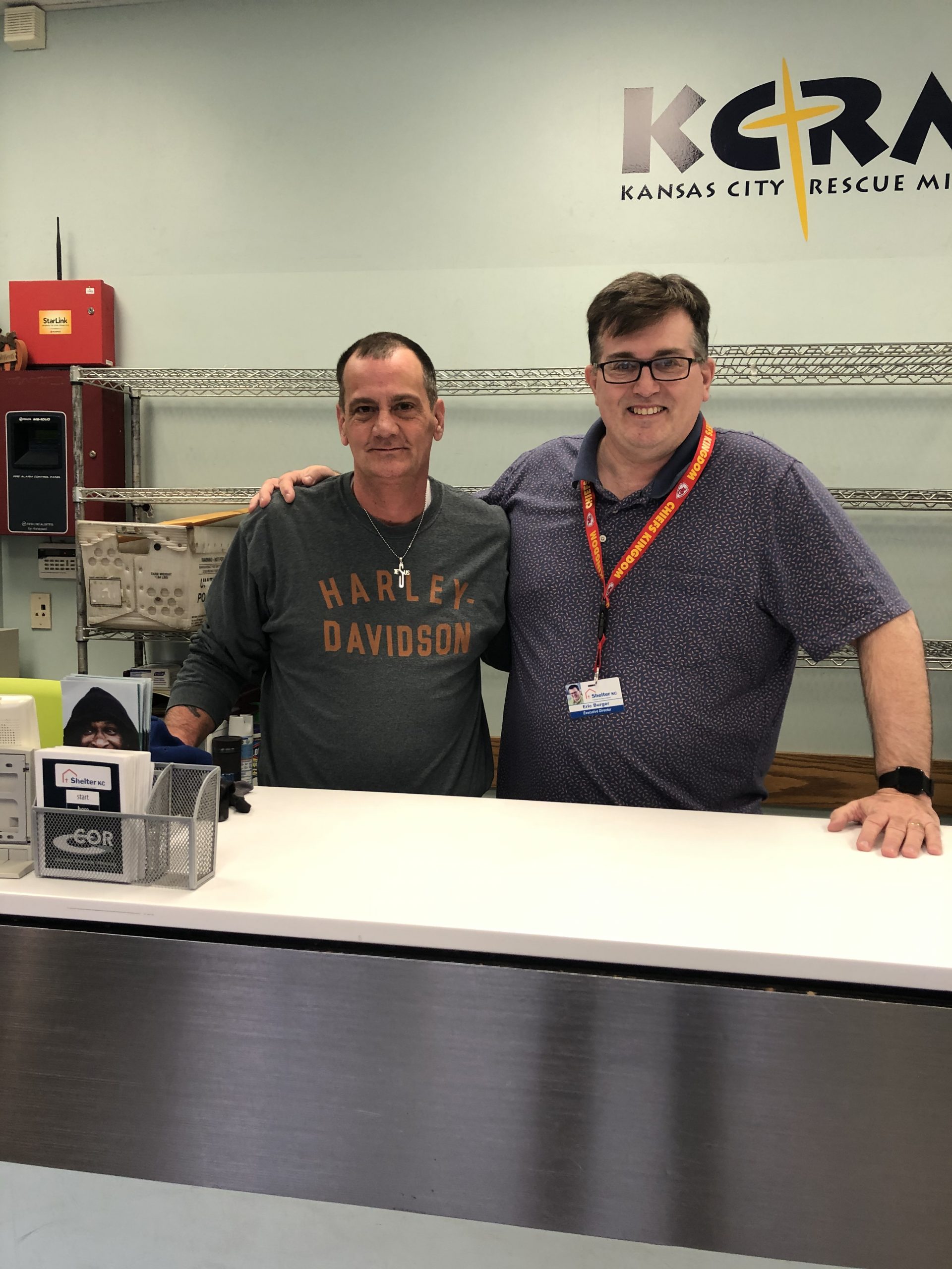 Rob and Eric smiling at a Kansas City Rescue Mission desk