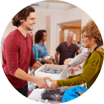 Man handing box of cans to smiling woman volunteer