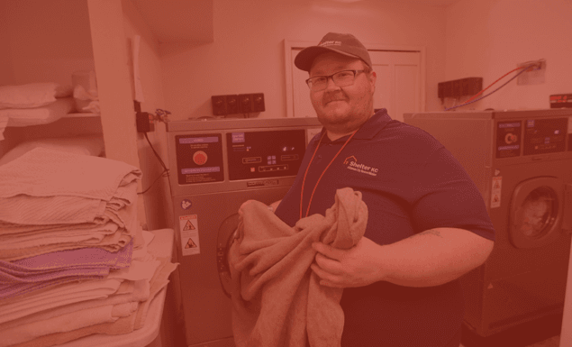 Shelter KC Volunteer washes towels in washing machine