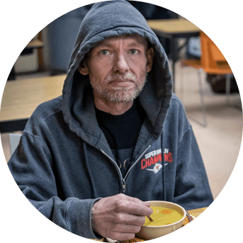 Stoic man eats soup and looks directly forward