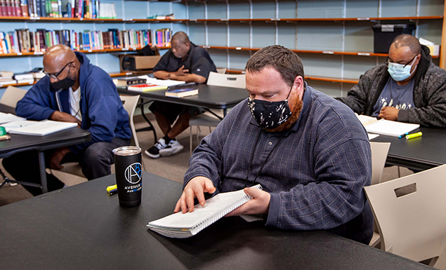 Men studying notebooks in Shelter KC library