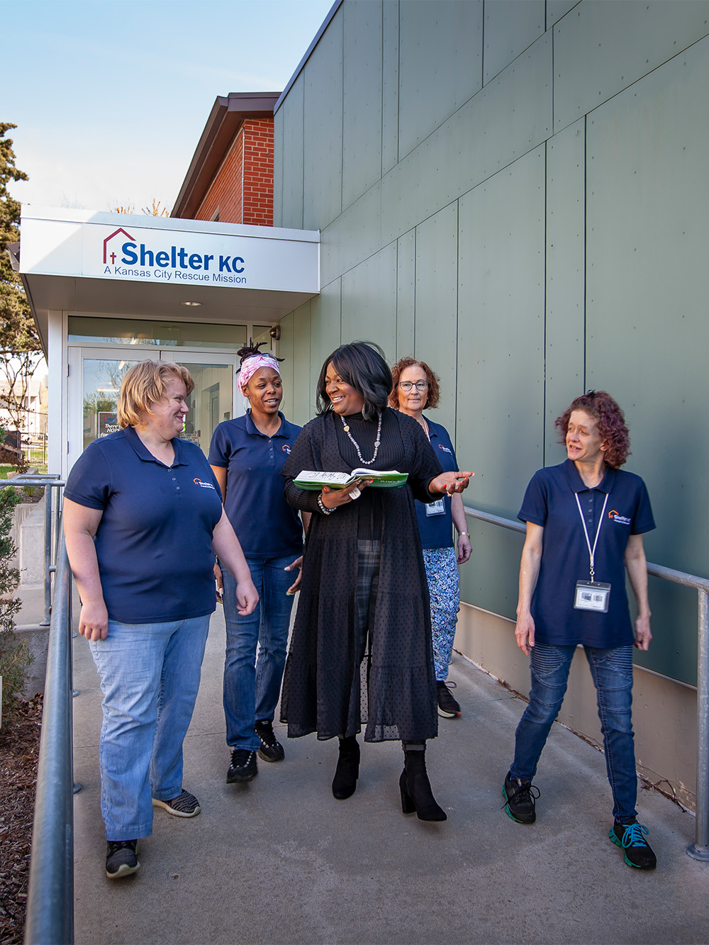 Women from the Shelter KC Women's ministry walk outside while reading bible