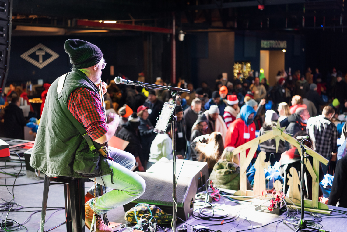 man playing guitar for a crowd of people